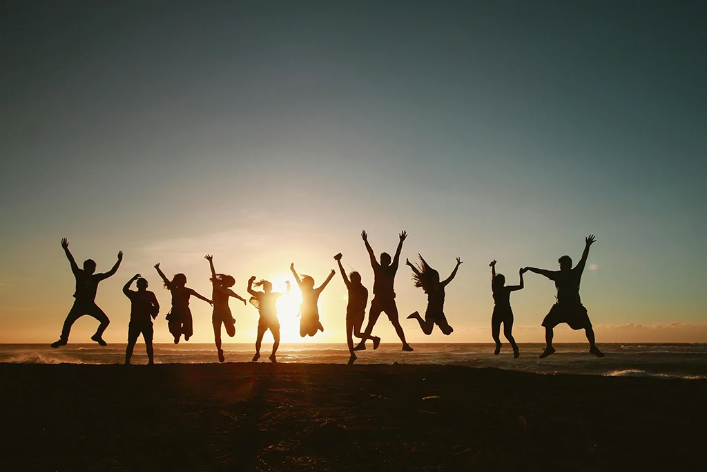 Groupe de gens sautant devant un couché de soleil